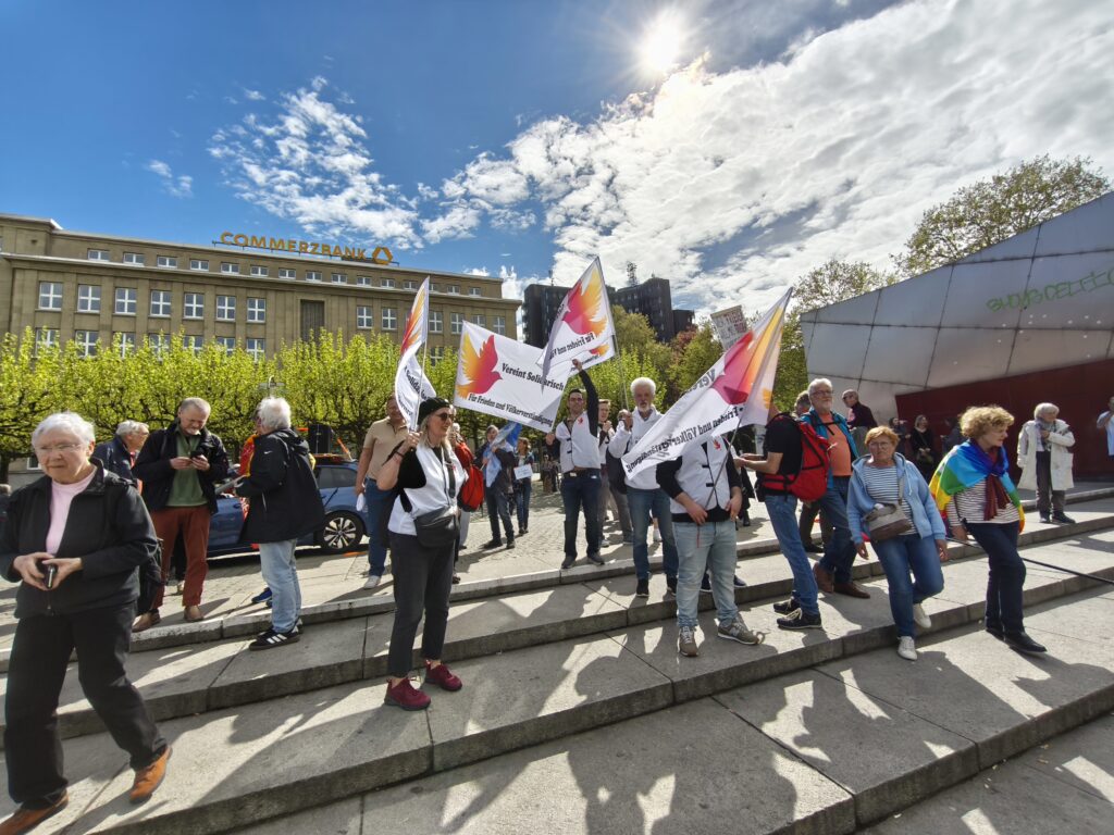 BSW Soest beim Ostermarsch 2025 in Dortmund mit weißen Fahnen und der orange-brombeerfarbenen Friedenstaube darauf.